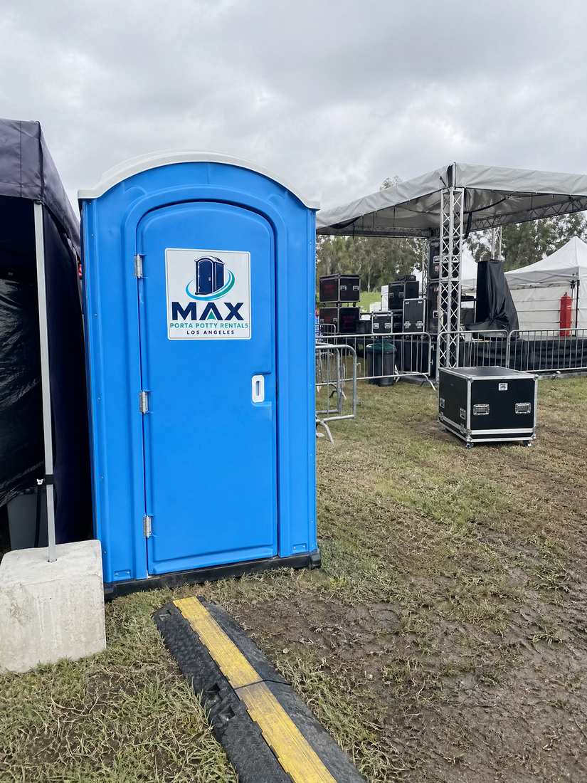Blue porta potty at a stage event behind catering